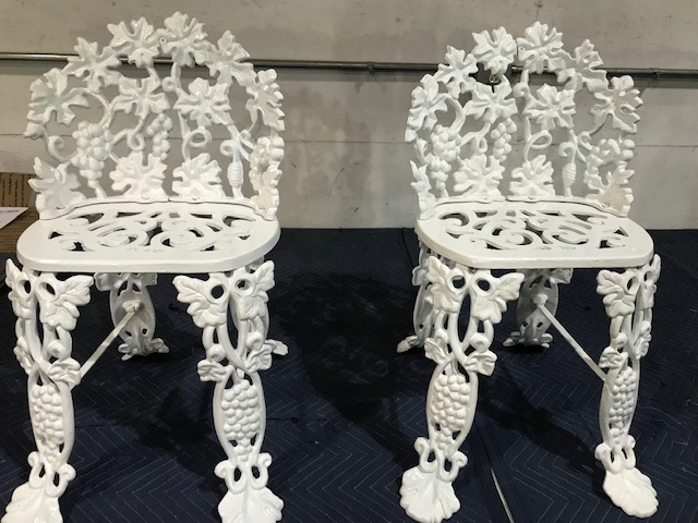 A pair of restored white cast iron chairs.