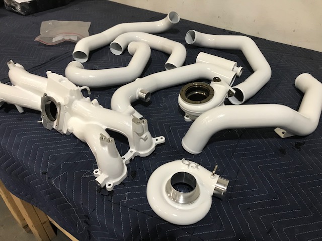 A set of white powder coated turbos and parts on a table.